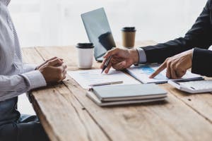 Close up of two colleagues' hands over business reports and financial charts