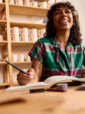 Comerciante sonriente escribiendo en un cuaderno en su tienda