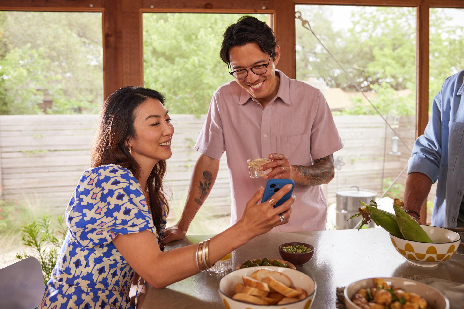 A man and woman smile joyfully while standing beside a table filled with an array of delicious food.